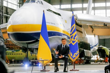 El presidente ucraniano Volodymyr Zelenskyy habla durante una conferencia de prensa teniendo de fondo el avión más grande del mundo, el An-225 Mriya de Antonov, en la fábrica de aeronaves Antonov en Kiev, Ucrania, el jueves 20 de mayo de 2021. (AP Foto/Efrem Lukatsky)