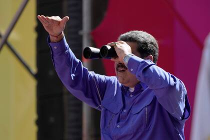 El presidente venezolano Nicolás Maduro mira a través de unos binoculares durante un mitin por el Día del Trabajo el domingo 1 de mayo de 2022, en Caracas, Venezuela. (AP Foto/Ariana Cubillos)