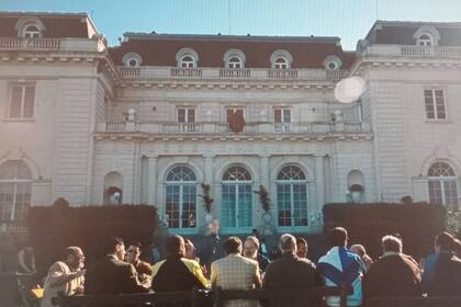 El presidente y sus hombres comparten un asado con sindicalistas, donde todo terminará mal; de fondo, la mansión de la estancia Abril