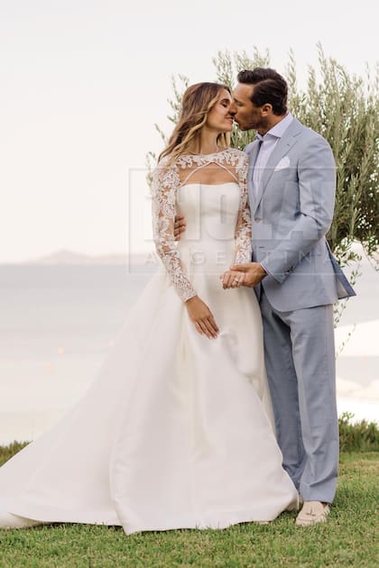 El primer beso de recién casados. Ella, con un espectacular traje confeccionado en seda mikado con chaqueta de encaje desmontable y él, con un traje de lino y detalles by Lacoste.