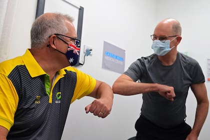 El primer ministro de Australia, Scott Morrison, choca el codo con el director médico del gobierno australiano, Paul Kelly, después de que ambos recibieron una dosis de la vacuna Pfizer/BioNTech contra la Covid-19 en el Castle Hill Medical Center en Sydney el 21 de febrero de 2021