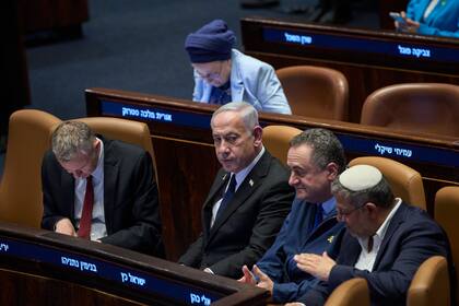 El primer ministro de Israel, Benjamin Netanyahu, rodeado por ministros del gobierno, asiste a una sesión del Knesset, el parlamento israelí, en Jerusalén, el lunes 14 de julio de 2025. (AP Foto/Ohad Zwigenberg)