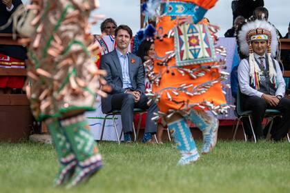 El primer ministro Justin Trudeau y el jefe Cadmus Delorme ven a danzantes durante la celebración de la aprobación de una transferencia de control de niños a cargo de la comunidad en la nación indígena Cowessess, Saskatchewan, el martes 6 de julio de 2021. (Liam Richards/The Canadian Press vía AP)
