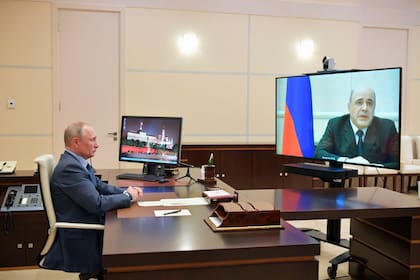 El primer ministros, Mijaíl Mishustin, (en la pantalla) junto a Vladímir Putin por videoconferencia.