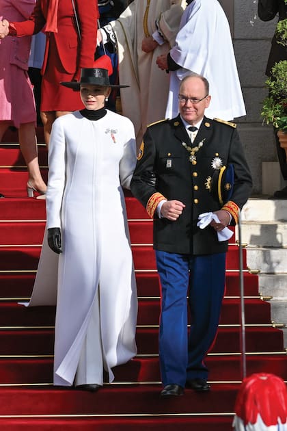 El príncipe Alberto junto a su mujer Charlene, deslumbrante con un original abrigo con capa de Akris. Lo combinó con polera, guantes de cuero de Dior y pamela y accesorizó con pendientes de perlas y un broche de brillantes en forma de moño de Van Cleef & Arpels.