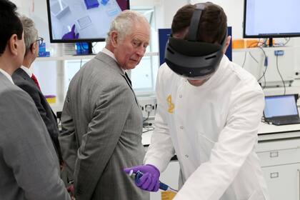 El príncipe Carlos de Gran Bretaña asiste a una demostración de cómo la realidad aumentada ayuda con la tecnología Hololens durante una visita a una nueva instalación de AstraZeneca en el Cambridge Biomedical Campus, Inglaterra, el martes 23 de noviembre de 2021. (Chris Jackson/PA vía AP)