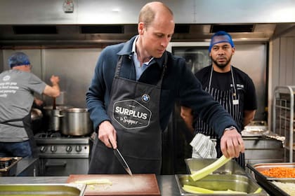 El príncipe Guillermo corta apio mientras ayuda a preparar una salsa boloñesa durante una visita a Surplus to Supper, una organización benéfica en Sunbury-on-Thames, Surrey, Inglaterra, el 18 de abril de 2024.