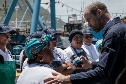 El príncipe Guillermo de Inglaterra recibe un regalo de una residente en Kalk Bay Harbour, cerca de Ciudad del Cabo, el 7 de noviembre de 2024. (Gianluigi Guercia/Pool Foto vía AP)