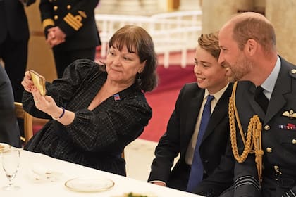 El príncipe William y su hijo George posan para una selfie con una de las invitadas a tomar el té en Buckingham.