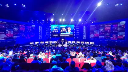 El público asistiendo a la final de la copa mundial de Gran Turismo 7; los pilotos están sentados en los simuladores al fondo de la imagen