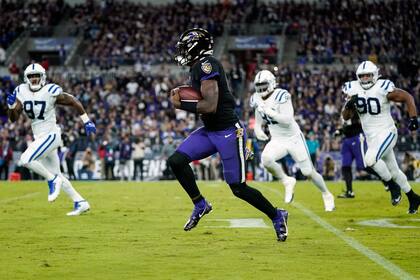 El quarterback de los Ravens de Baltimore Lamar Jackson (8) se escapa de los defensores de los Colts de Indianapolis durante la primera mitad de su juego de NFL el lunes 11 de octubre de 2021 en Baltimore. (AP Foto/Julio Cortez)