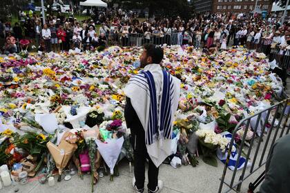 El rabino Yossi Friedman habla ante una multitud reunida frente a flores colocadas ante el Pabellón Bondi, en la playa Bondi, el martes 16 de diciembre de 2025, luego de un tiroteo ocurrido el domingo en esa playa, en Sidney, Australia