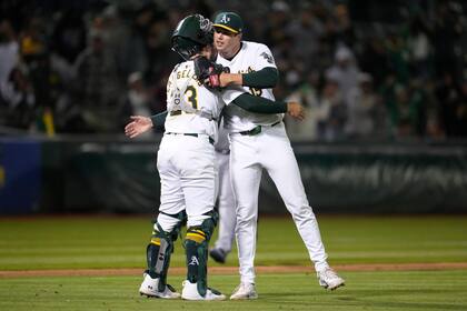 El receptor de los Atléticos de Oakland, Shea Langeliers, a la izquierda, celebra con el lanzador Mason Miller después de que los Atléticos derrotaron a los Reales de Kansas City en Oakland, California, el miércoles 19 de junio de 2024. (AP Foto/Jeff Chiu)