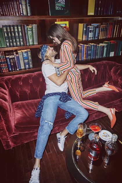 El, remera con inscripción y jeans (Levis), zapatillas de lona (Adidas). Ella, tailleur pantalón de lino rayado (Mirta Armesto), zapatos de gamuza (Prüne)