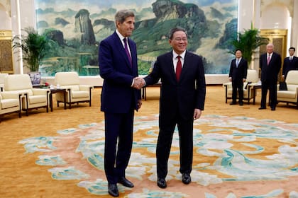 El representante especial de clima John Kerry, a la izquierda, y el primer ministro de China, Li Qiang, se estrechan la mano antes de una reunión en el Gran Salón del Pueblo en Beijing el martes 18 de julio de 2023. (Florence Lo/Pool Foto via AP)