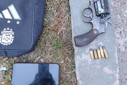 El revolver calibre .38 Smith & Wesson, con tres balas y dos vainas servidas junto al celular y la morra del detenido.