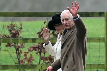 El rey Carlos III de Gran Bretaña y la reina Camila de Gran Bretaña saludan cuando salen después de asistir a un servicio en la Iglesia de Santa María Magdalena en Sandringham en el este de Inglaterra el 11 de febrero
 (JUSTIN TALLIS / AFP)