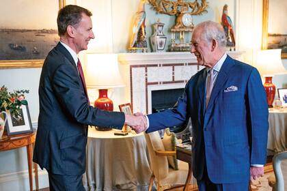 El rey Carlos III saluda al canciller de Hacienda británico, Jeremy Hunt, en el Palacio de Buckingham, en Londres. (Aaron Chown / POOL / AFP)