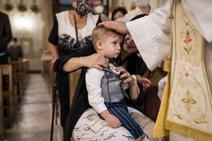 El sacerdote Salvatore Cubito bendice a Samuel De Luca durante el bautismo en Catania, Italia