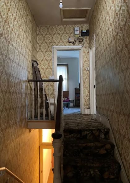 El sector de las escaleras: alfombras manchadas y un empapelado deteriorado