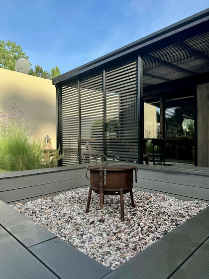 El sector del fogonero en el jardín cuenta un gran banco revestido con el mismo deck que la galería para crear “un efecto de continuidad”.