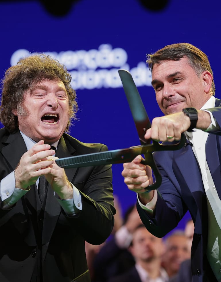 El senador brasileño Flavio Bolsonaro, a la derecha, sostiene unas tijeras gigantes, acompañado por el presidente argentino Javier Milei, durante la convención del Partido Liberal en la que Bolsonaro fue confirmado como candidato presidencial del partido, en São Paulo, el sábado 25 de julio de 2026. (Foto AP/Ettore Chiereguini)