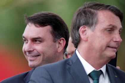 El senador brasileño Flavio Bolsonaro sonríe cerca de su padre, el presidente de Brasil, Jair Bolsonaro, en Brasilia, el 21 de noviembre de 2019