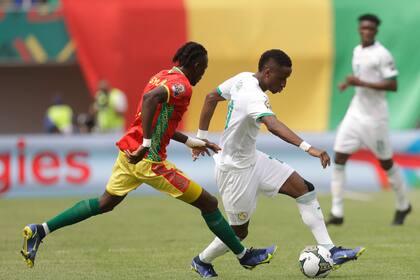 El senegalés Bouna Sarr, izquierda, busca robar el balón al guineano Issiaga Sylla durante un duelo de la Copa Africana de Naciones 2022 por el Grupo B, en el Estadio Omnisport de Bafoussam, Camerún, el viernes 14 de enero de 2022. (AP Foto/Sunday Alamba)