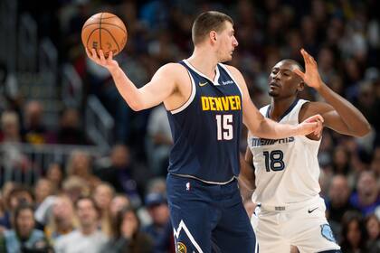 El serbio Nikola Jokic busca enviar un pase frente a Bismack Biyombo, de los Grizzlies de Memphis, en el partido del jueves 28 de diciembre de 2023 (AP Foto/David Zalubowski)