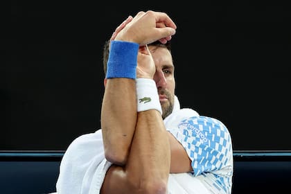 El serbio Novak Djokovic estirando sus brazos: con molestias físicas venció al francés Enzo Couacaud y avanzó a la tercera ronda de Australia