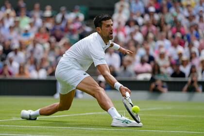El serbio Novak Djokovic hace una devolución al italiano Jannik Sinner en un duelo de cuartos de final de Wimbledon, el martes 5 de julio de 2022 (AP Foto/Alastair Grant)