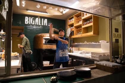 El show de los pizzaiolos revoleando la masa estirada a mano antes de llevarla al horno de piedra refractaria fabricado a mano en Nápoles