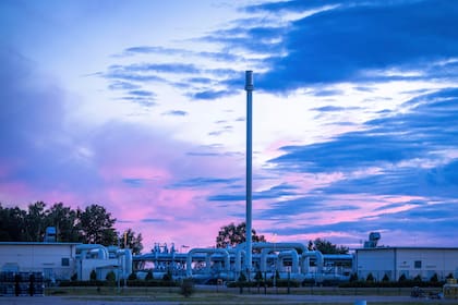 El sol sale por detrás de sistemas de tuberías y dispositivos de apagado en la estación receptora de gas del gasoducto báltico Nord Stream 1 y la estación de transferencia del ducto OPAL en Lubmin, Alemania, el lunes 11 de julio de 2022. ( Jens Buettner/dpa via AP)