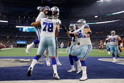 El tacle ofensivo de los Cowboys de Dallas Terence Steele celebra con Connor McGovern y otros compañeros su atrapada para un touchdown de 1 yarda en el triunfo ante Washington el domingo 26 de diciembre del 2021. (AP Photo/Michael Ainsworth)
