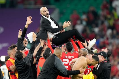El técnico de Marruecos Walid Regragui es alzado por los jugadores tras la victoria 1-0 ante Portugal en los cuartos de final del Mundial, el sábado 10 de diciembre de 2022, en Doha, Qatar. (AP Foto/Martin Meissner)
