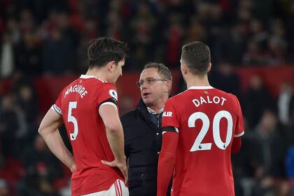 El técnico del Manchester United Ralf Rangnick (centro) habla con Harry Maguire (izquierda) y Diogo Dalot al final del partido contra Tottenham Hotspur en la Liga Premier, el 12 de marzo de 2022, en Manchester. (AP Foto/Rui Vieira)