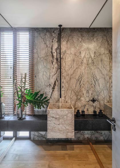 El toilette, revestido en mármol ‘Fantastic Grey’ pulido con mesada en granito ‘Negro Brasil’ (Cavatori Mármoles), se agranda gracias al espejo que cubre enteramente la pared lateral.