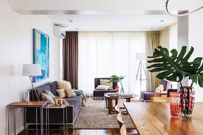 El toque verde en el living lo dan hojas esculturales en delicados floreros