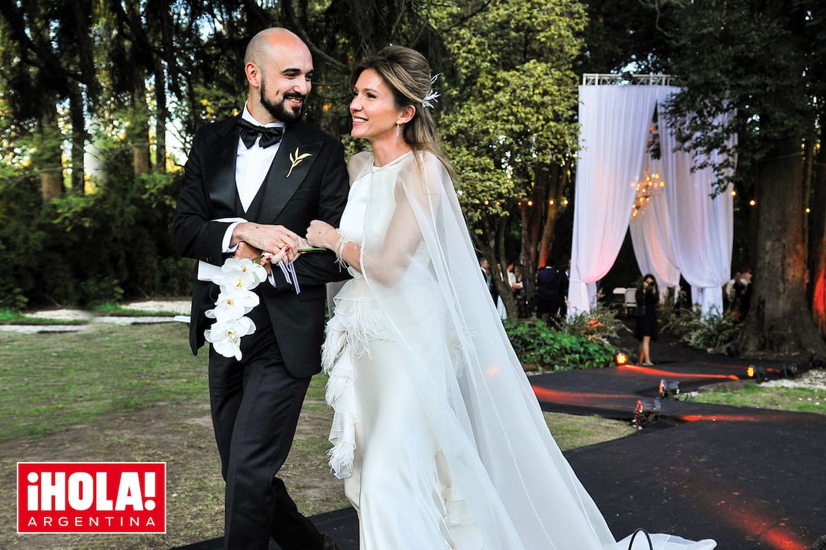 El traje de la novia fue diseñado por Fabián Zitta. Se trata de un fourreau al bies en seda natural color marfil, de corte sirena, escote americano, espalda baja y falda con apliques de volados en organza de seda y plumas en cascada que forman una gran cola. Remata con una capa de corte imperio. Los zapatos al tono eran de cabritilla nacarada de corte retro y el peinado, con pines de perlas, cristales y plumas sobre un recogido desestructurado. Él lució un smoking hecho a medida, con líneas elegantes, en negro pleno, igual que el moño. La joya que llevaba prendida en la solapa es una pieza bañada en oro –confeccionada por Fendra– inspirada en un símbolo que representa la familia que están formando.