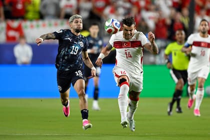 El turco Abdulkerim Bardakci disputa el balón con el paraguayo Julio Enciso