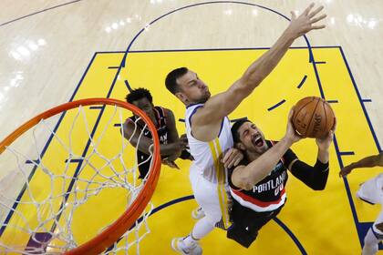 El turco Enes Kanter, de Portland, trata de aguantar la marca y la tapa de Bogus