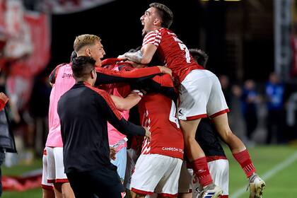 El uruguayo Mauro Méndez en la cima del festejo de los jugadores de Estudiantes, luego del agónico gol de Heredia