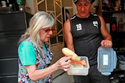 Carlos Alfaro, de 51 años, le muestra a su madre, Dilcy Marmol, de 77 años, la comida que recibió en una cocina móvil de alimentos administrada por el gobierno, durante la pandemia, en su casa, en Ciudad de México
