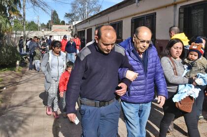 Un policía ayuda a un hombre a ir hasta la mesa para votar