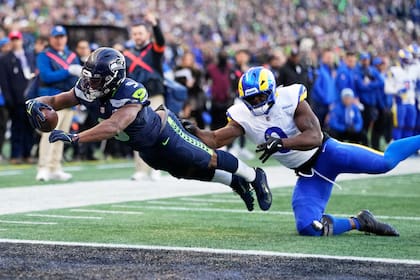 El vuelo de Kenneth Walker III, de los Seahawks de Seattle, se lanza para anotar frente a Byron Young, de los Rams de Los Ángeles