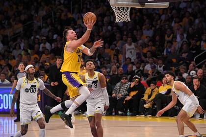 El vuelo de Luka Doncic frente al base de los Jazz, Keytone George, Jordan Clarkson y Johnny Juzang, en el debut del esloveno en los Lakers. (AP Foto/Mark J. Terrill)