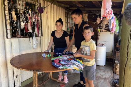 Elena (izq.), Milagros (centro) y Miguel trabajan en el emprendimiento de alfombras y gomitas en la galería de su casa