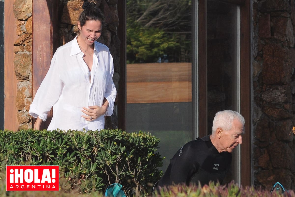 Elina, con la mano en su incipiente pancita de embarazada, contempla a su marido mientras prepara el equipo para practicar kitesurf.