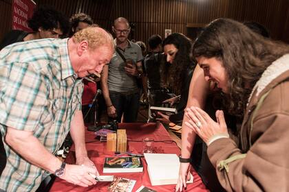 Emerick firmando autógrafos a las personas que participaron de la charla organizada por Instituto Nacional de la Música
