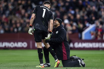 Emiliano Martínez es atendido en su muslo derecho por un integrante del cuerpo médico de Aston Villa, durante el partido con Chelsea